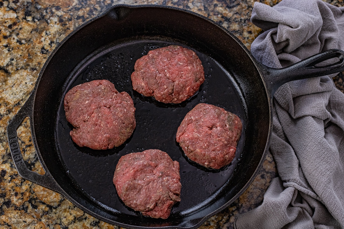 uncooked hamburger steaks in a cast iron skillet