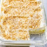 coconut cream pie bars in a baking dish with a slice out of it