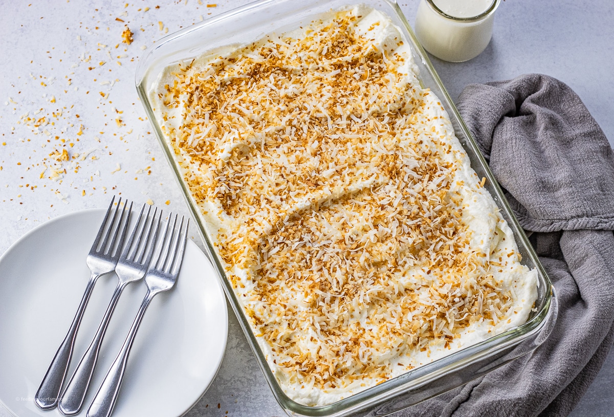 baking dish filled with coconut cream pie bars topped with toasted coconut.