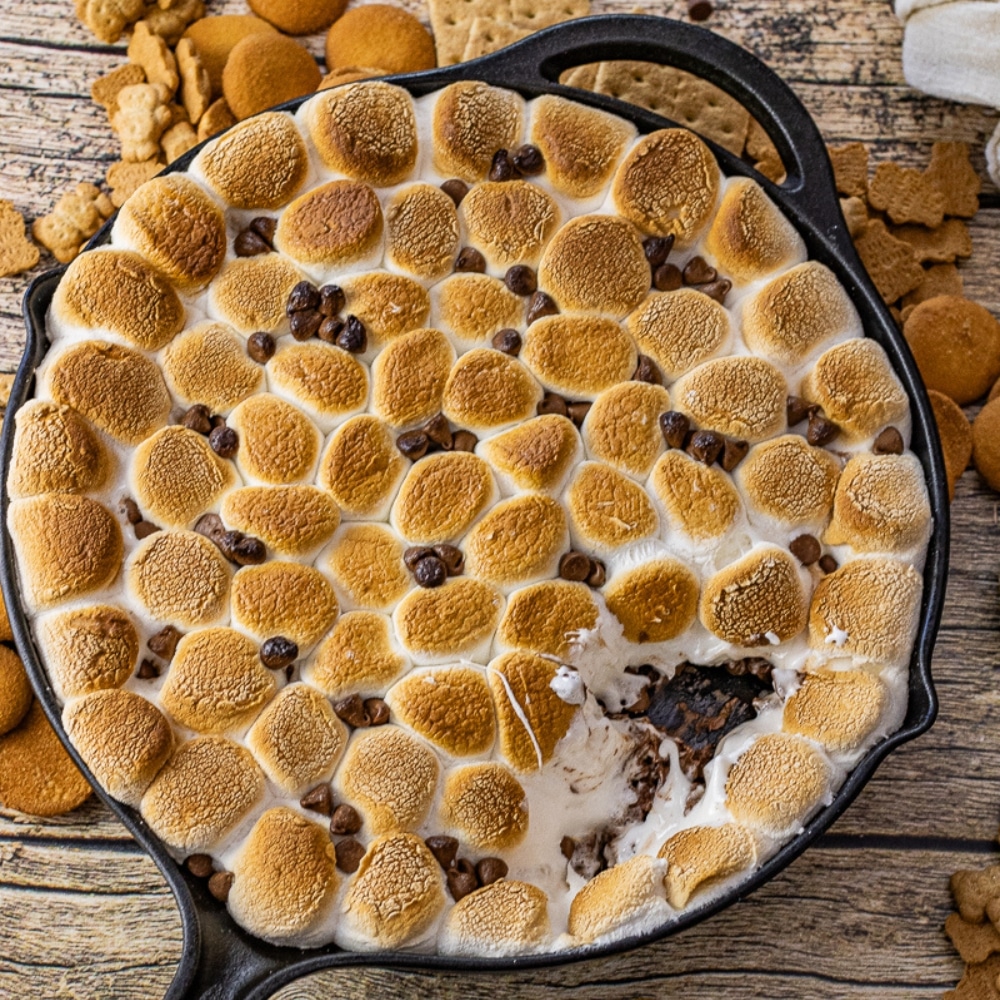 golden brown marshmallows on top of melted milk chocolate in a cast iron skillet