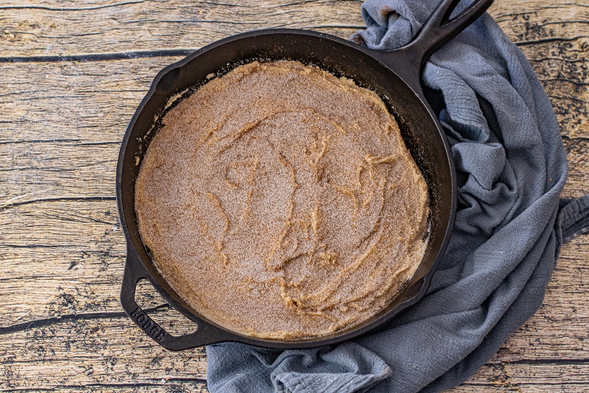 uncooked snickerdoodle dough topped with cinnamon and sugar in a cast iron skillet