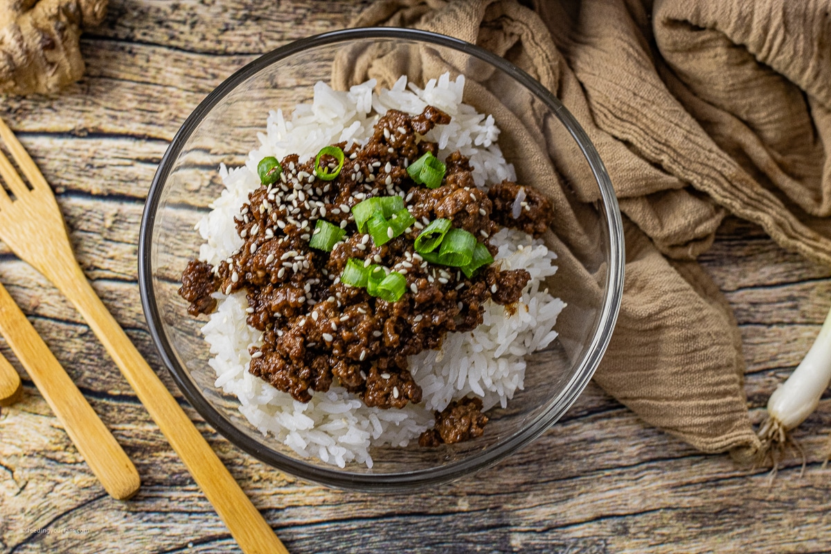 ground beef cooked in a savory soy sauce on top of rice in a glass bowl