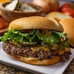 smashed cheeseburger in a brioche bun topped with lettuce, tomatoes, pickles and grilled onions