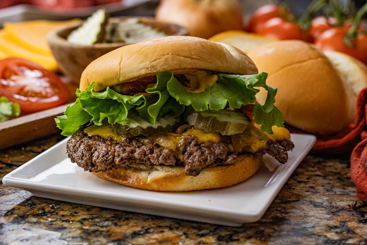 burger topped with cheese, pickles and lettuce on a brioche bun