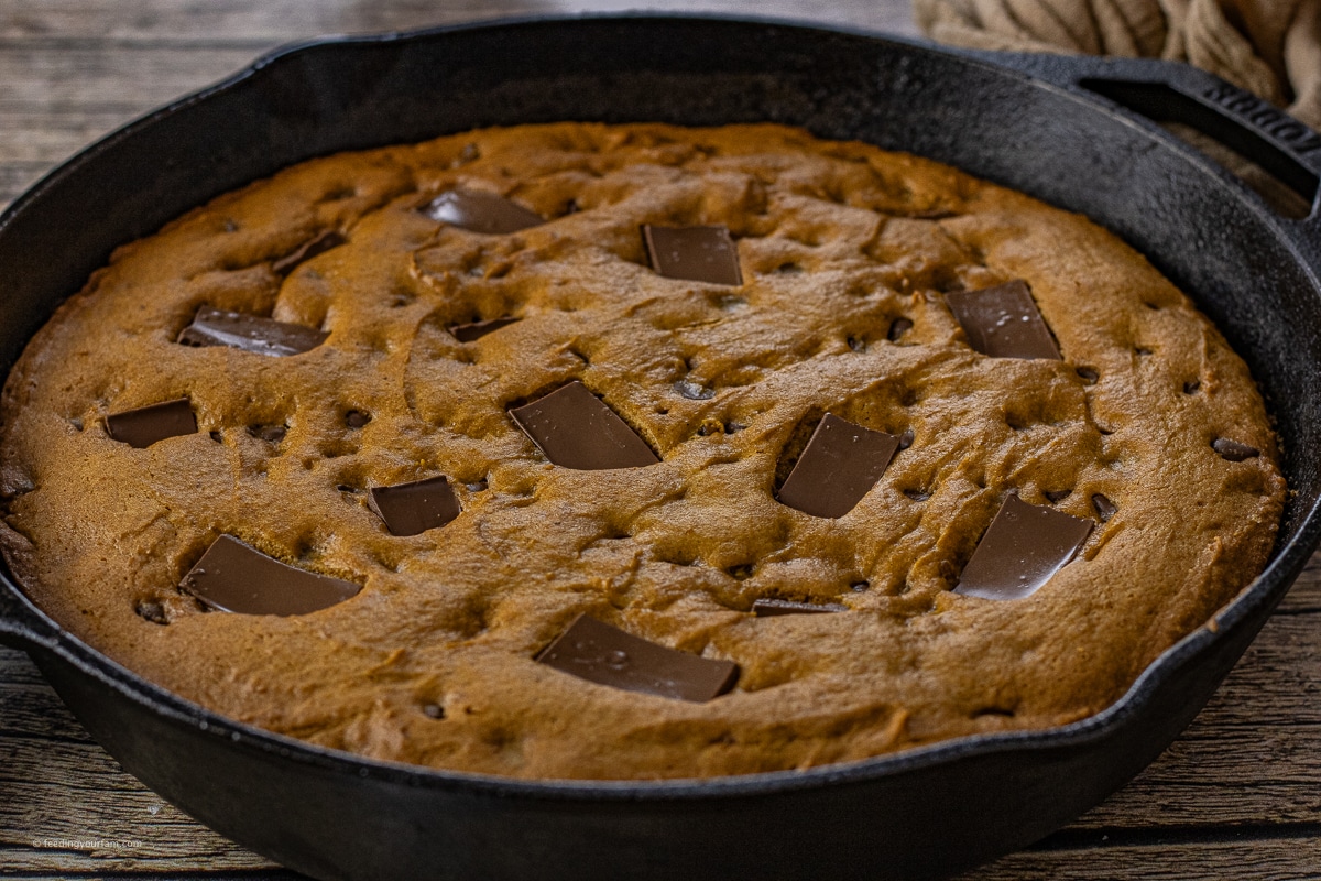 cast iron skillet with a pumpkin chocolate chip cookie baked inside it