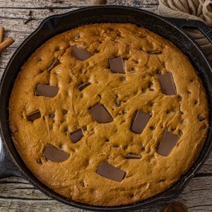 cast iron skillet with a pumpkin chocolate chip cookie baked in it