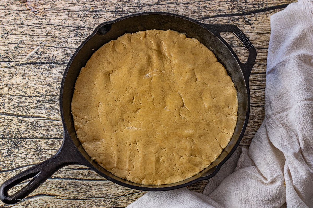 peanut butter cookie dough uncooked in a cast iron skillet 