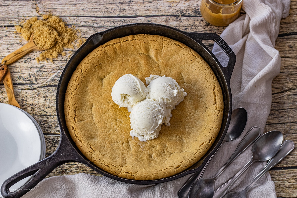 cast iron skillet with a peanut butter cookie topped with vanilla ice cream scoops