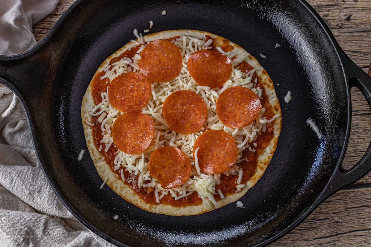 uncooked tortilla pepperoni pizza in a cast iron skillet 