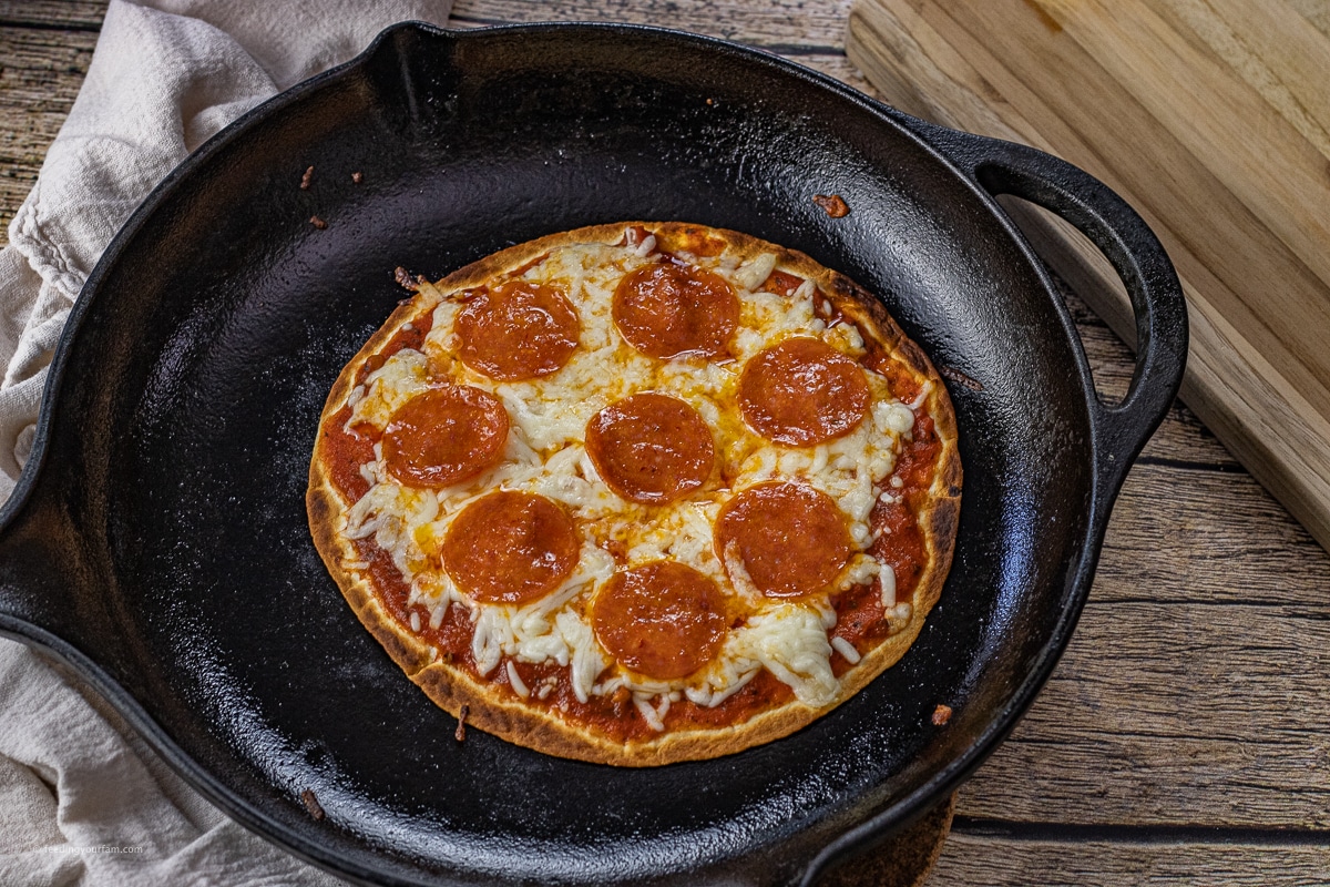 cast iron skillet with an cooked pizza on tortilla 