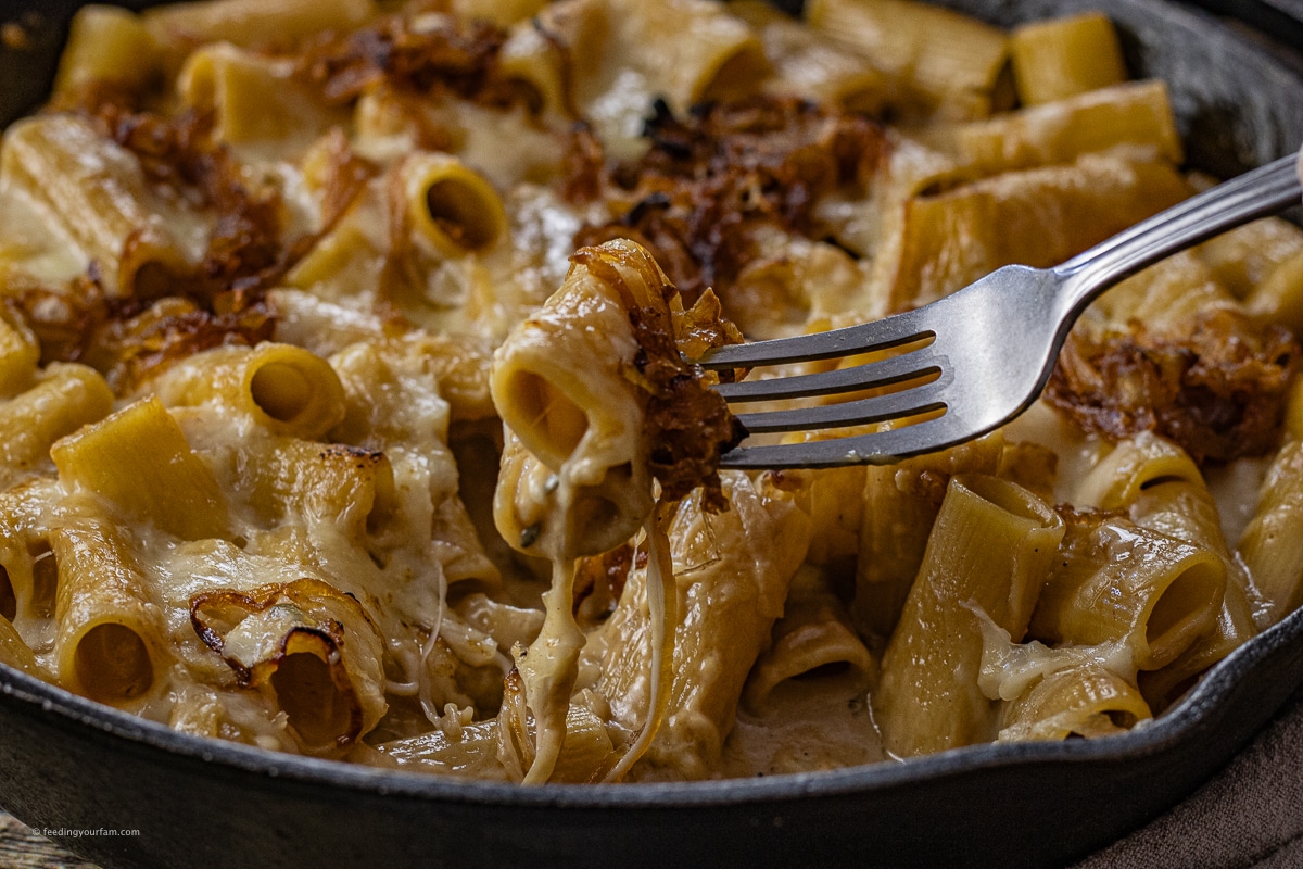 fork lifting up rigatoni in a french onion sauce