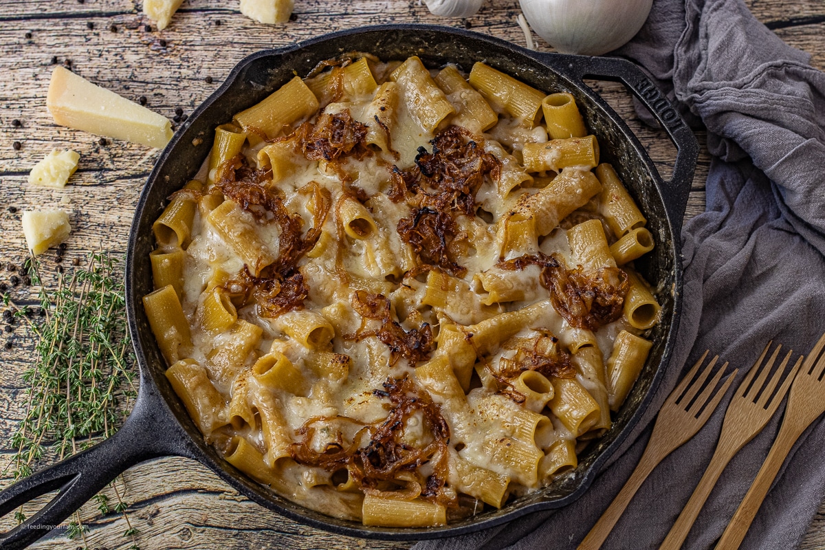 french onion pasta in a cast iron skillet topped with carmelized onions and melted Swiss cheese