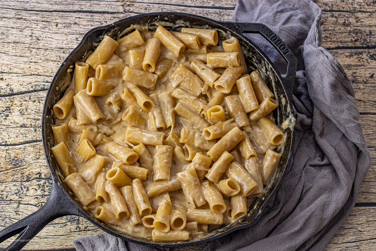 rigatoni pasta in a creamy caramelized onion sauce in a cast iron skillet