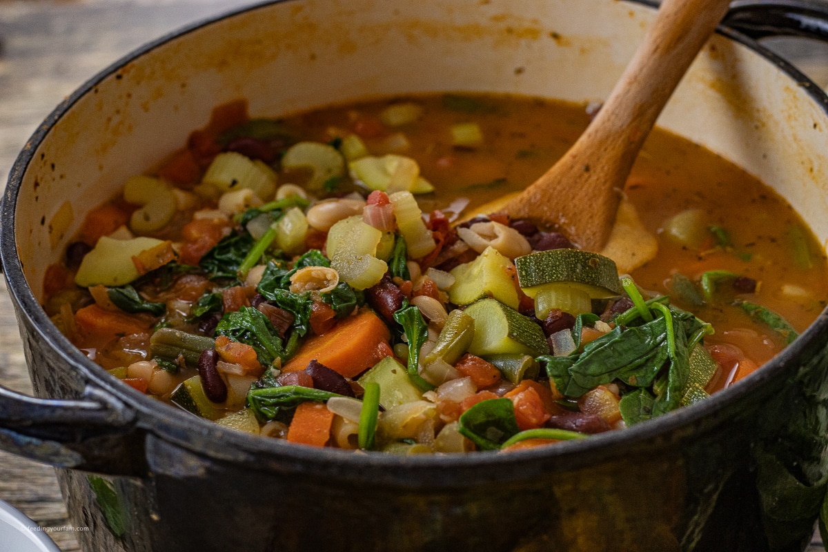 wooden spoon scooping up a spoonful of minestrone soup 