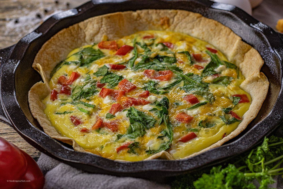 tortilla egg bake with spinach and red peppers in a cast iron pie pan