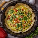 eggs, red peppers, spinach and cheese all baked in a tortilla in a cast iron pie pan