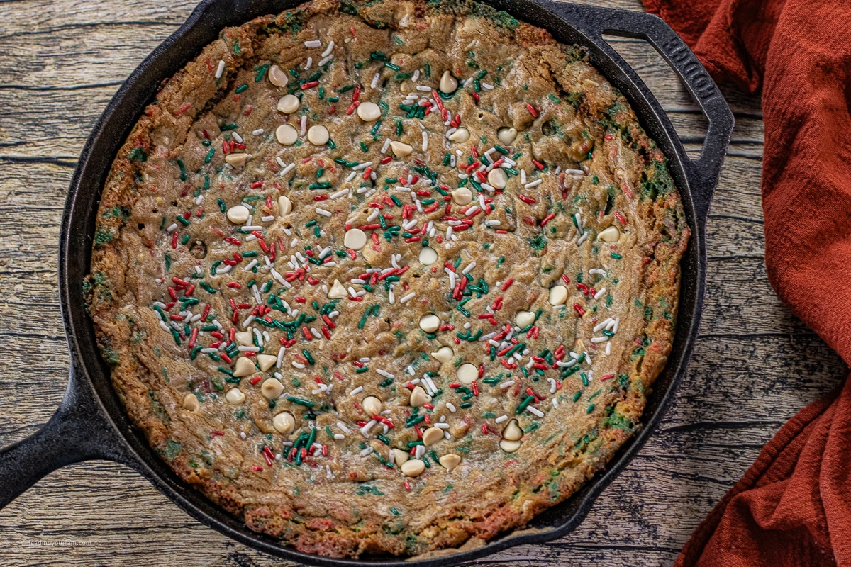 cast iron skillet cookie with red and green sprinkles and white chocolate chips