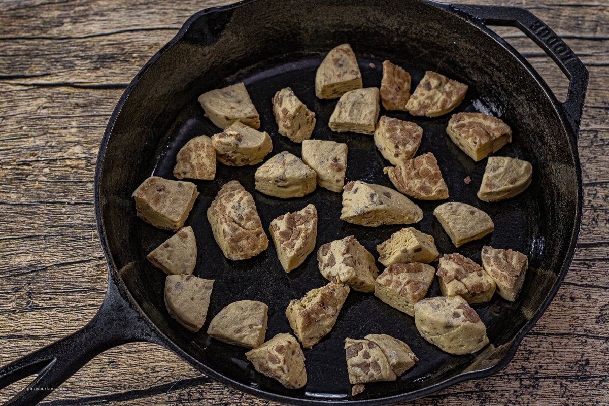 cut up pieces of cinnamon rolls in a cast iron skillet