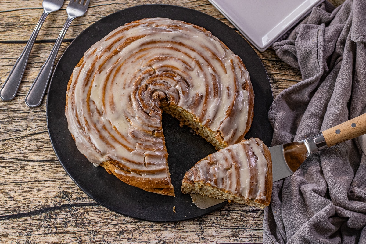 giant cinnamon roll cake with a slice out of it