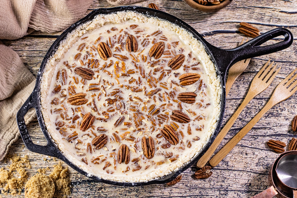 unbaked pecan pie in a cast iron skillet topped with pecan pieces