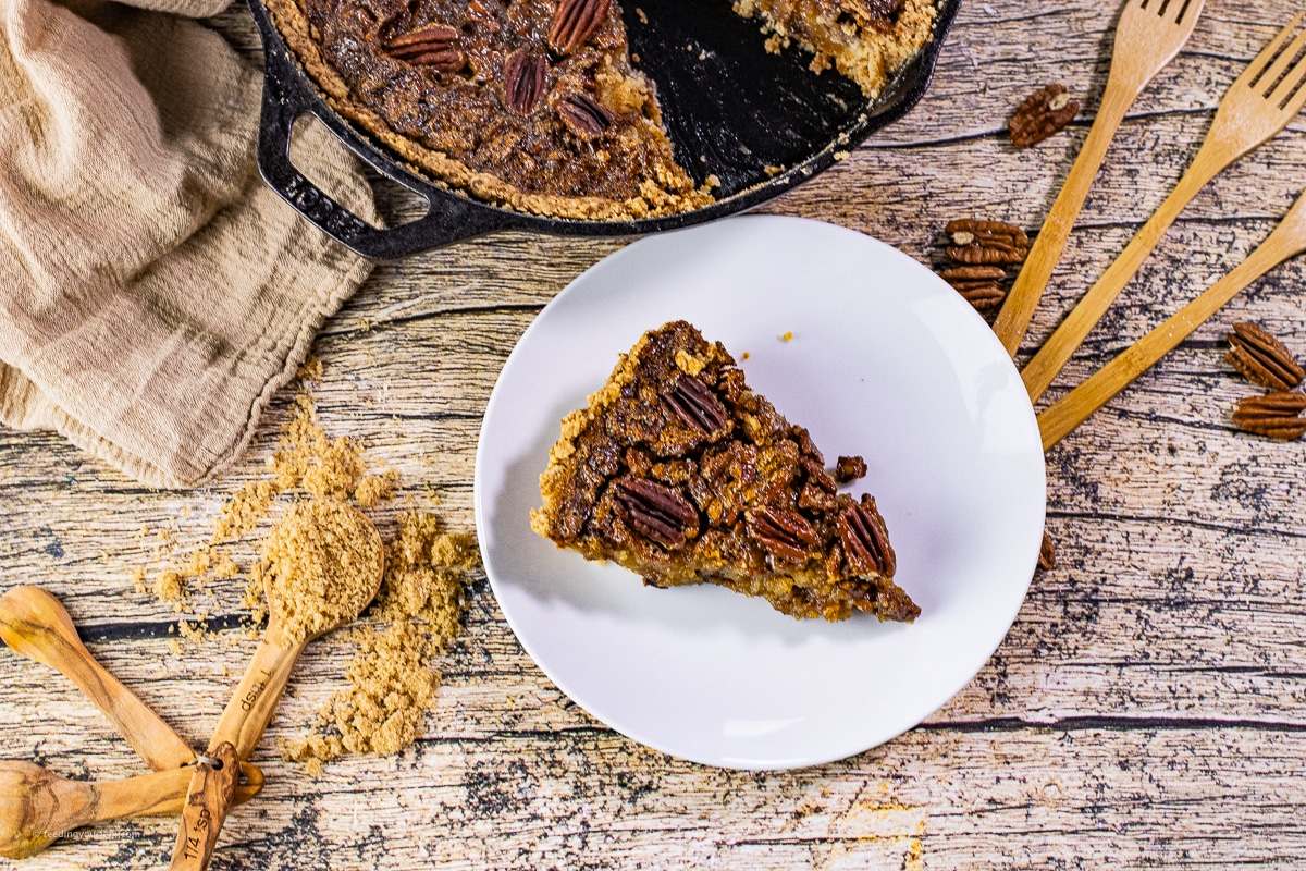 slice of pecan pie on a white plate cut from a skillet of pecan pie