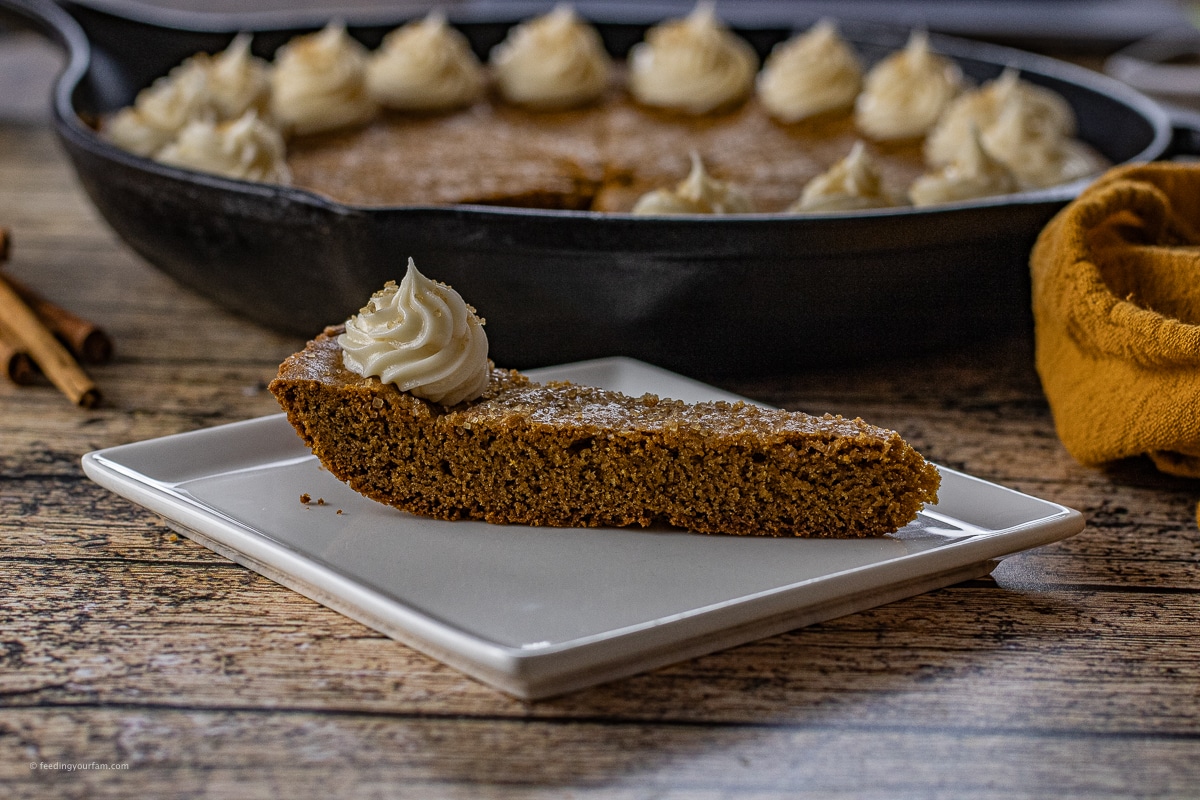 slice of gingerbread skillet cookie topped with a small dollop of cream cheese frosting. 