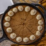 cast iron skillet with a gingerbread cookie baked in it topped with cream cheese frosting