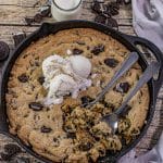 cookies and cream cookie baked in a cast iron skillet and topped with scoops of vanilla ice cream