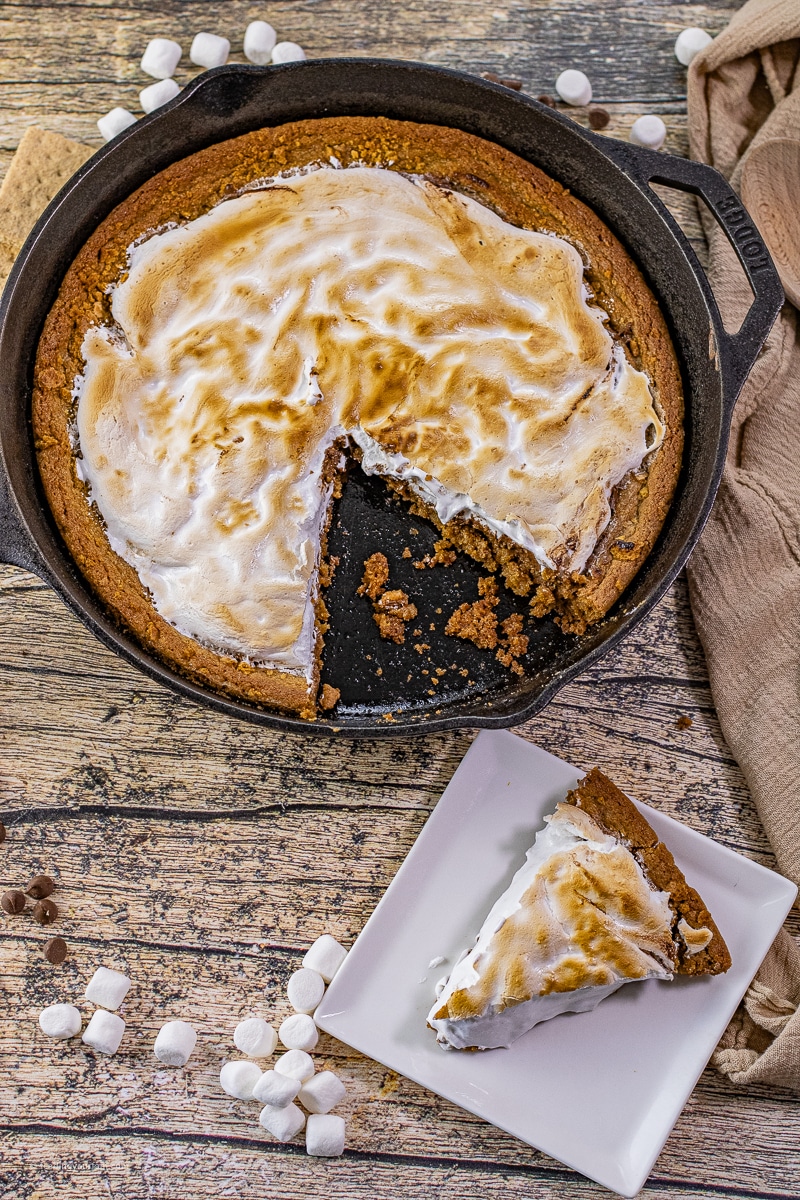 graham cracker cookie base in a cast iron skillet topped with melted chocolate and toasted marshmallow