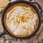 graham cracker cookie in a cast iron skillet topped with chocolate and toasted marshmallow