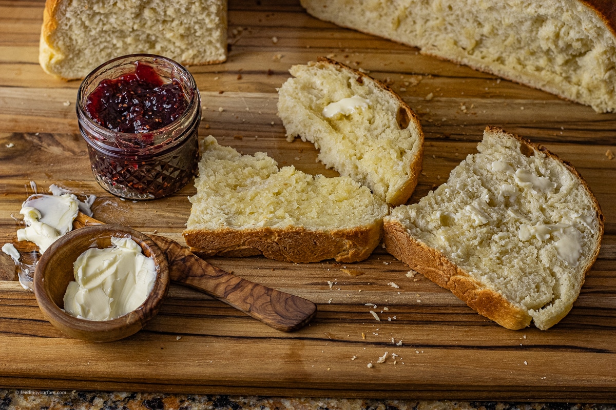 homemade bread slices on a wooden cutting board. The bread is topped with butter