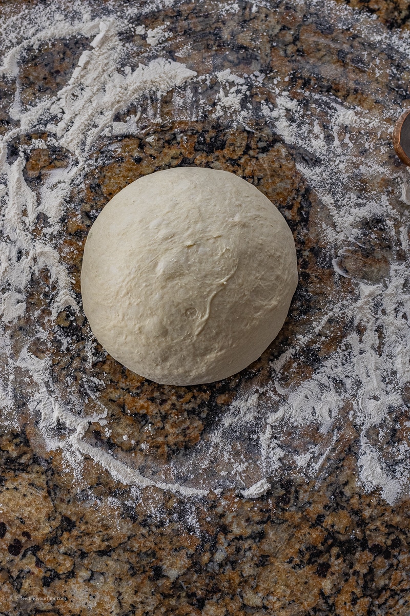 round ball of bread dough on a floured surface