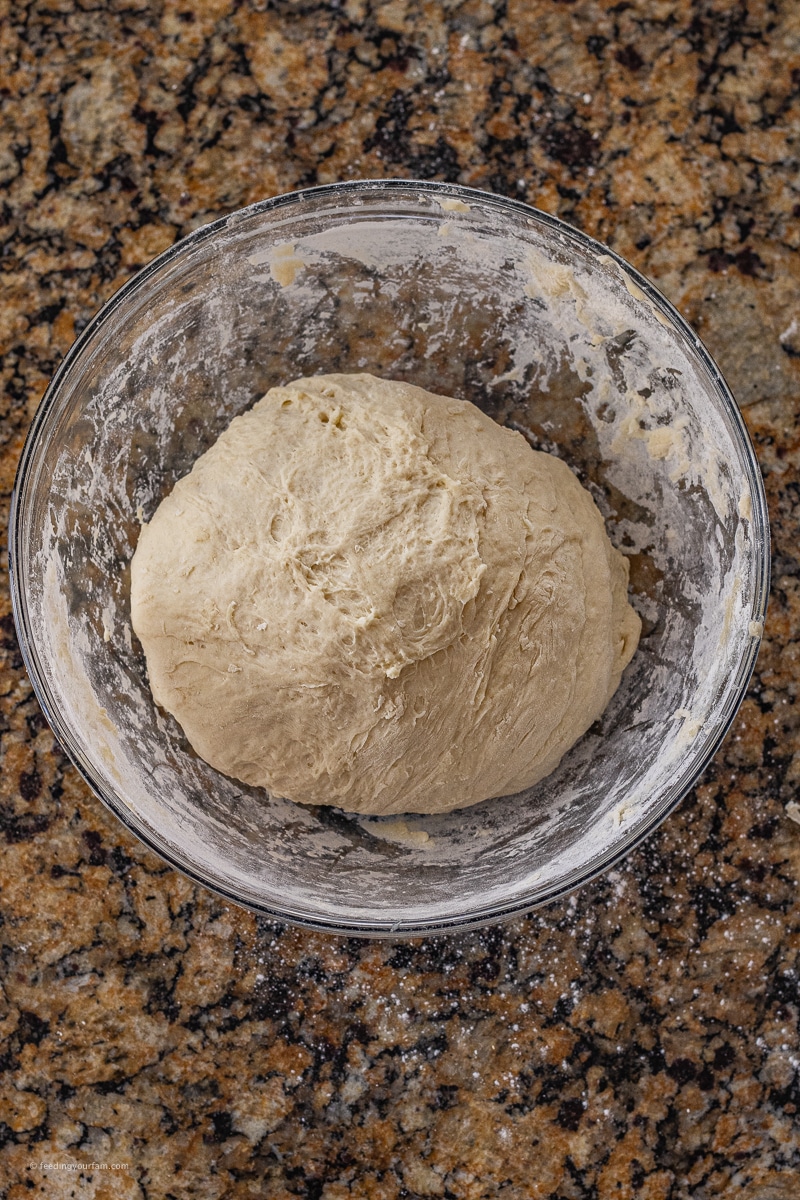 round ball of bread dough in a glass mixing bowl