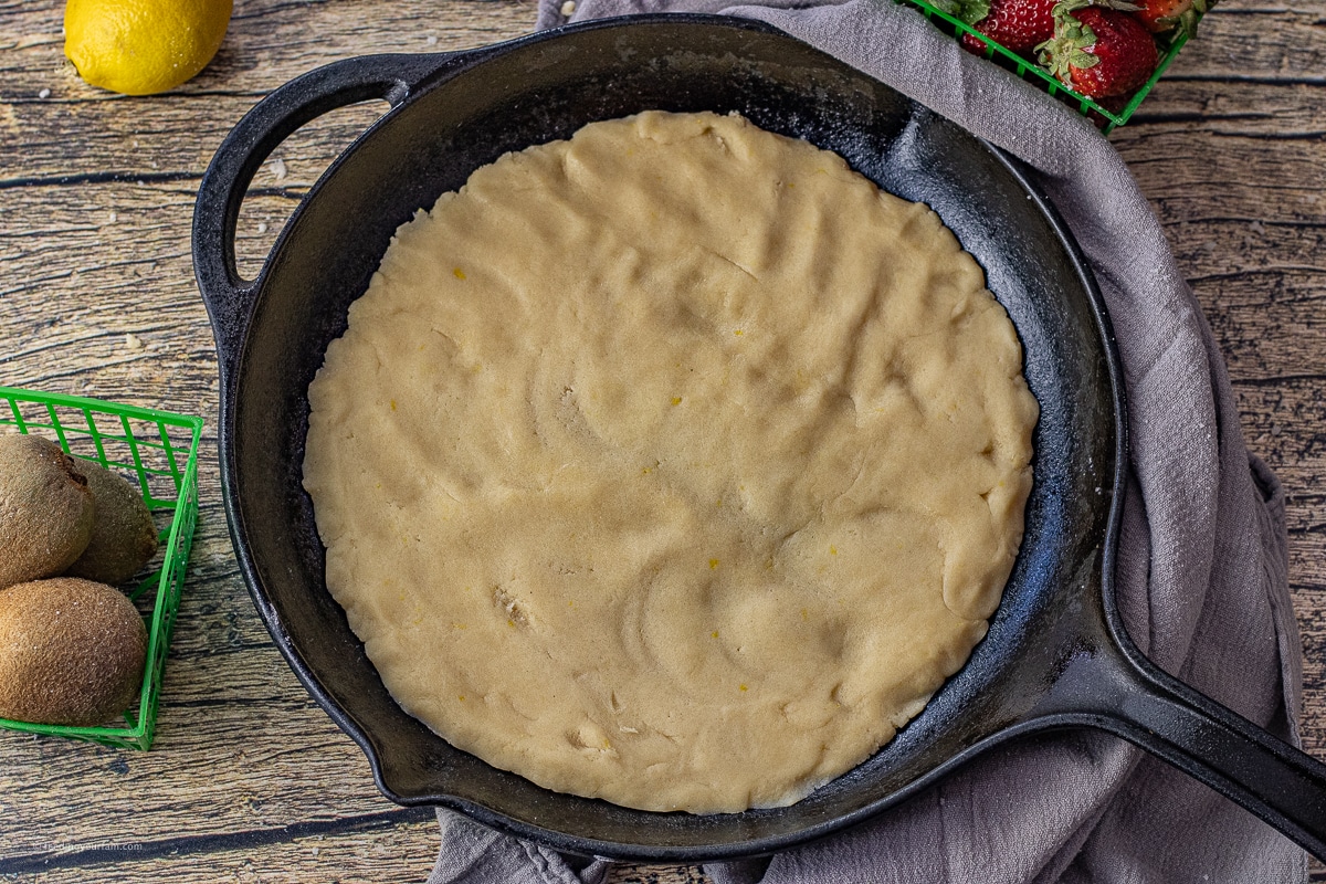 sugar cookie dough pressed into a cast iron skillet