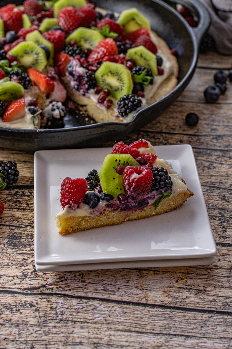 slice of fruit pizza with a lemon sugar cookie base on a white square plate