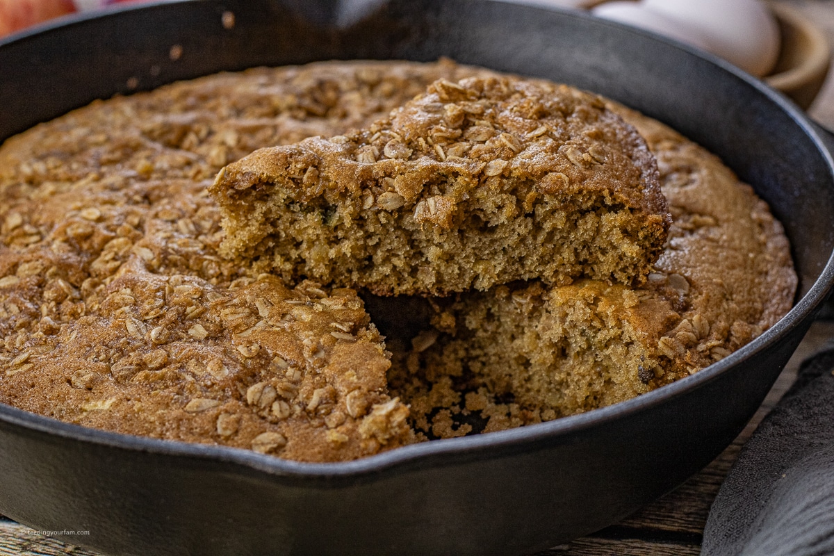 slice of apple cinnamon cake on top of the cake in a skillet