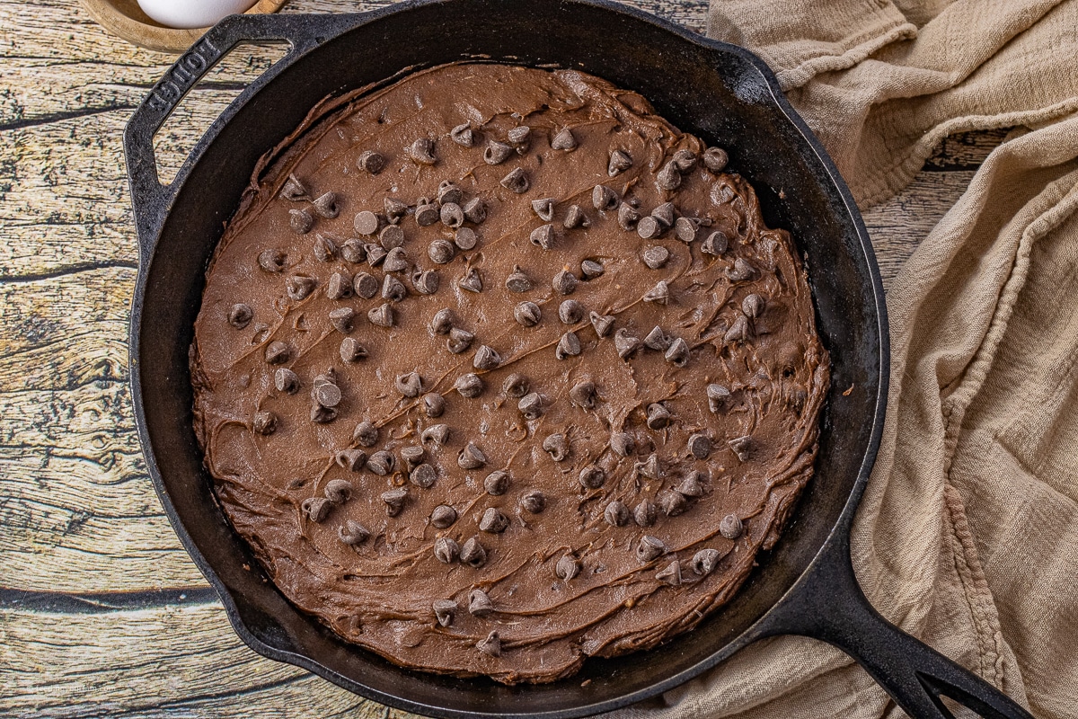 uncooked double chocolate chip cookie dough in a cast iron skillet