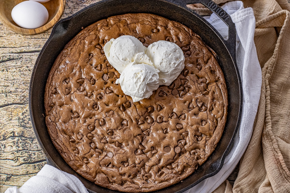 chocolate skillet cookie topped with scoops of vanilla ice cream