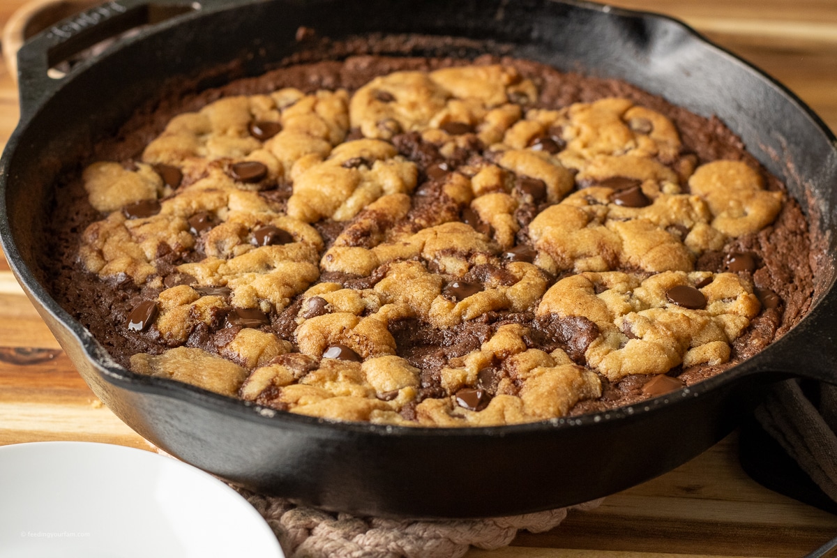 brownie topped with chocolate chip cookie batter baked in a cast iron skillet