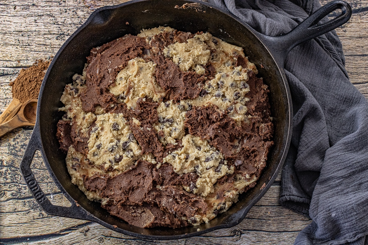 raw cookie and brownie batter in a cast iron skillet 