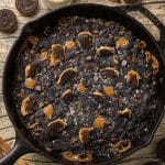 giant skillet cookie with dark cocoa cookie topped with black and white oreos and caramel