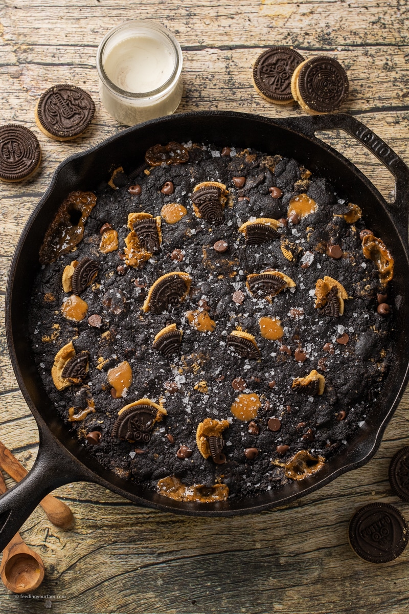 giant skillet cookie with dark cocoa cookie topped with black and white oreos and caramel