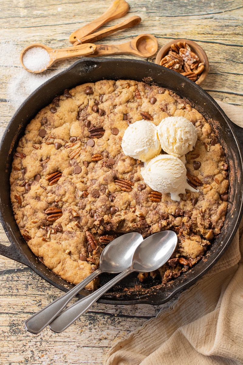 pizookie in a cast iron skillet with pecans and chocolate chips