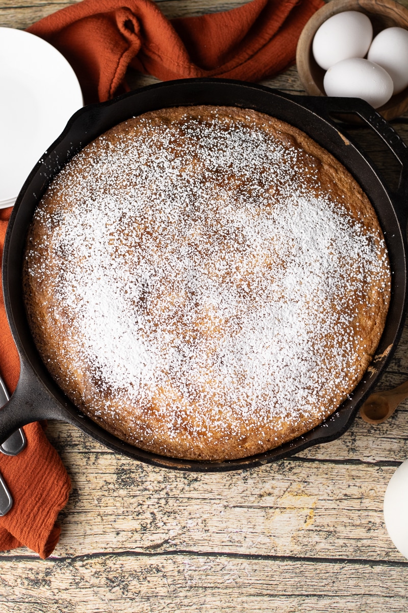 butter cake topped with powdered sugar in a cast iron skillet 