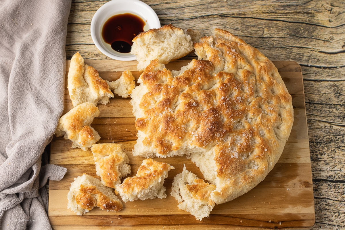 looking down on a round loaf of focaccia that has been torn into pieces
