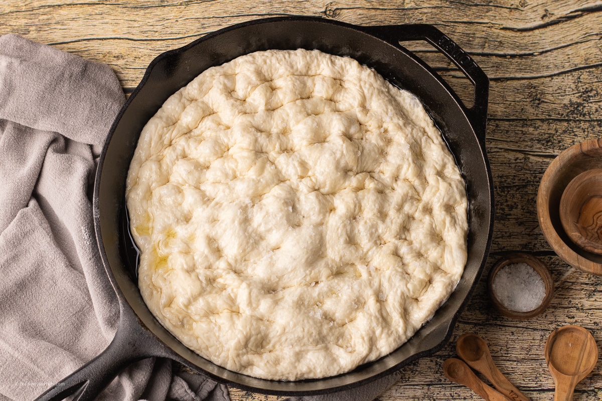 uncooked, bubbly focaccia in a cast iron skillet