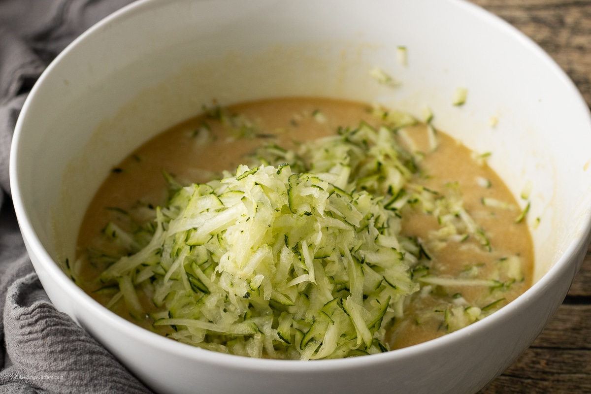 close up of grated zucchini in a mixing bowl