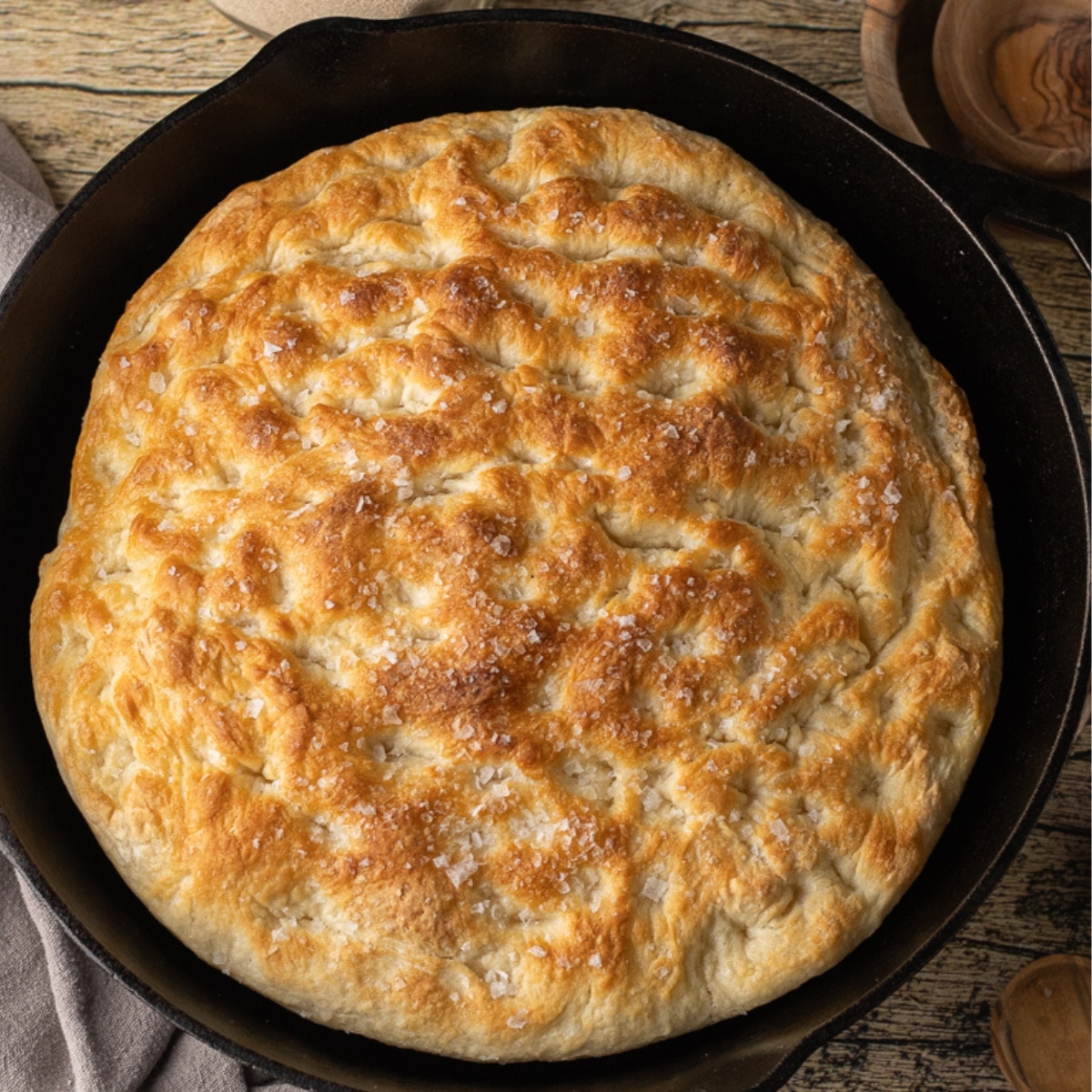 top view of a golden brown focaccia bread baked in a cast iron skillet