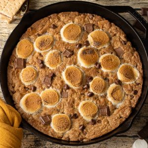 Brown Butter S’mores Skillet Cookie baked in a cast iron skillet with golden edges, melted chocolate, and toasted marshmallows on top, ready to be served warm.