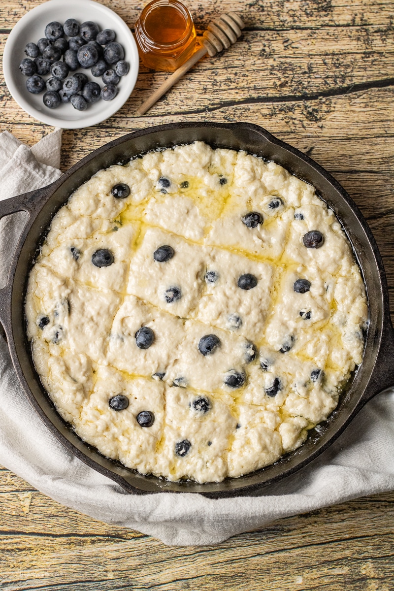 unbaked biscuit dough with blueberries in a cast iron skillet